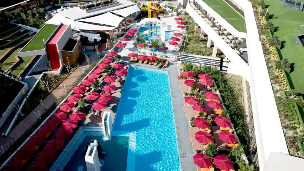 Where to Stay in Portland? 12 Top Rated Places in 2024 3 An aerial view of a luxurious resort complex. The resort features a large swimming pool surrounded by red umbrellas, a water park with slides and attractions, and lush green landscaping. There are also multiple buildings, including a restaurant and a bar, visible in the background.