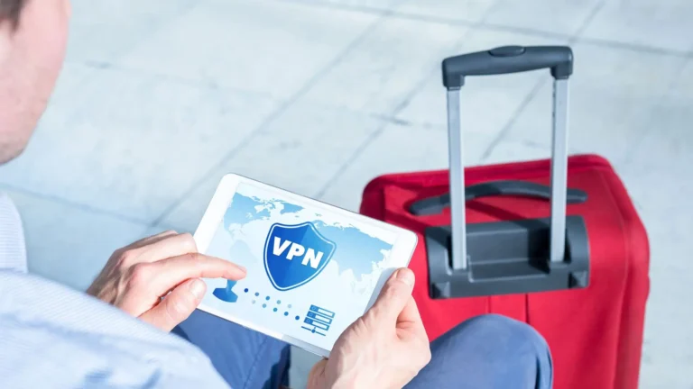 A person holding a tablet displaying a VPN security graphic sits next to a red suitcase, suggesting secure internet use while traveling.